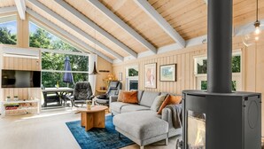 Un salon moderne avec une cheminée, des poutres en bois et une grande fenêtre.
