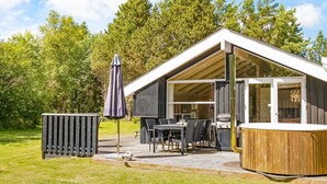 Un espace extérieur moderne, aménagé en patio, avec une table à manger, des chaises et un barbecue.
