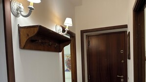 Un couloir avec un banc en bois, une porte en bois sombre et des luminaires fixés au mur.