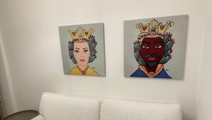 Deux œuvres d’art encadrées sont accrochées au mur, au-dessus d’un canapé blanc.