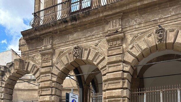 Un bâtiment en pierre doté de portes en arc de cercle et d’un portail en métal.