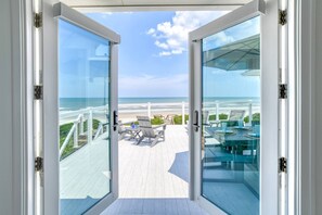 A glass door leading to a deck with outdoor seating and a view of the beach. - Beachfront Paradise, New Pool and Hot Tub, Private Boardwalk, Six King Suites, $300 in Free Tickets! (St. Augustine)