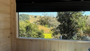 A wooden cabin room with a large window overlooking a green landscape. - Ranch style living with incredible views! (Cambria)