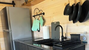 A modern kitchen with a built-in refrigerator, a stove, and a sink. There are wooden cabinets and a countertop. - Ranch style living with incredible views! (Cambria)