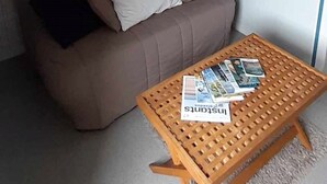 Huoneessa on ruskea sohva, puinen sohvapöytä, jossa on lehtiä, ja raidallinen seinä, jossa on kehystettyjä kuvia.