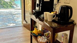Une pièce avec une table en bois sur laquelle se trouvent une machine à café, des tasses et un panier rempli de citrons. Une fenêtre donne sur un balcon d’où l’on peut admirer un paysage montagneux.