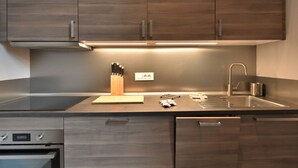 A modern kitchen with wooden cabinets, a stainless steel sink, and a built-in oven. - Lovely apartment for 4 people with A/C, WIFI, TV and patio (Milan)