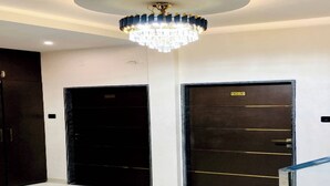 Un'accogliente hall moderna con un lampadario, due porte nere e una scala.
