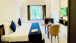Una camera d'albergo con un letto, una scrivania, una sedia, una televisione e una finestra con tende.