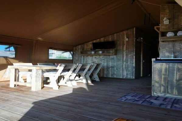 Een houten interieur met een eettafel en stoelen, een ingebouwde televisie en opbergplanken.