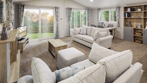 Ein modernes Wohnzimmer mit Sofa, Hocker, Fernseher und Bücherregal.