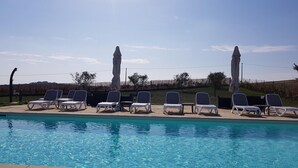 A swimming pool with lounge chairs and umbrellas. - Farmhouse in Marche with Pool and Coastal Views (Fermo)