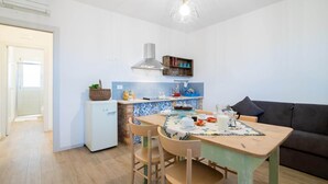 A compact kitchen with a dining area, a small refrigerator, a stove, and a hanging light fixture. - Farmhouse in Marche with Pool and Coastal Views (Fermo)