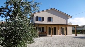 A two-story house with a covered porch and a gravel driveway.