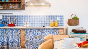 A kitchen with a blue and white patterned backsplash, wooden shelves, and a hanging pot rack.