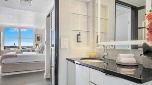 Una camera da letto moderna con un ampio letto, bagno con cabina doccia in vetro e vista sull'esterno.