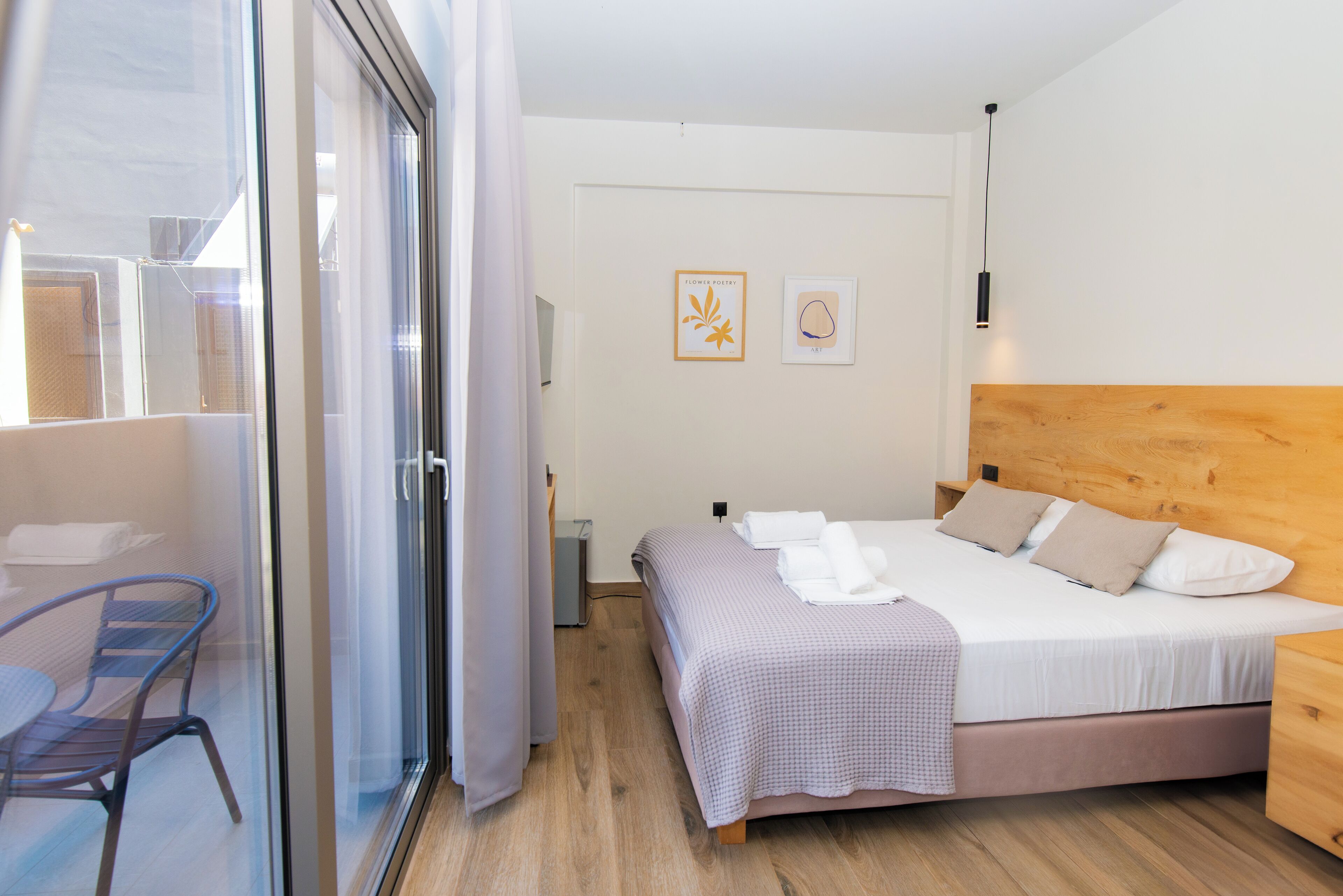 Une chambre à coucher comprenant un lit, une chaise, une table de chevet et une fenêtre donnant sur l’extérieur.