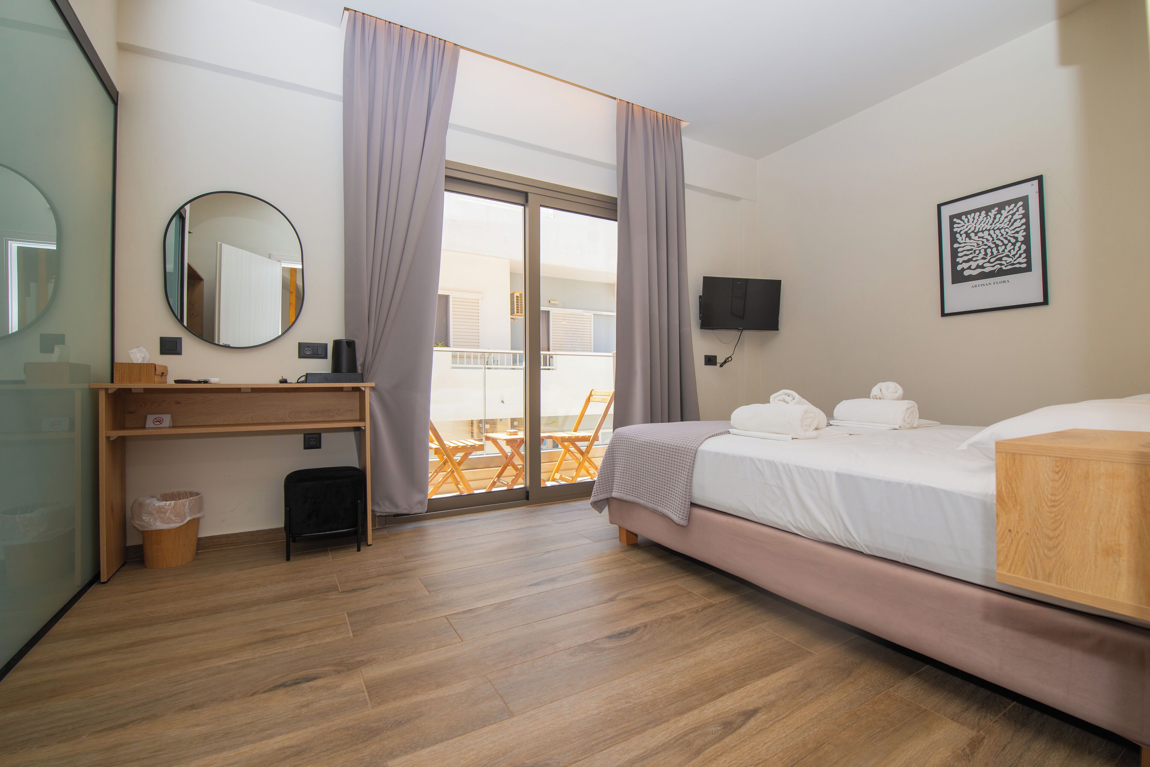A hotel room with a bed, a desk, a chair, a TV, a window with curtains, and a balcony.