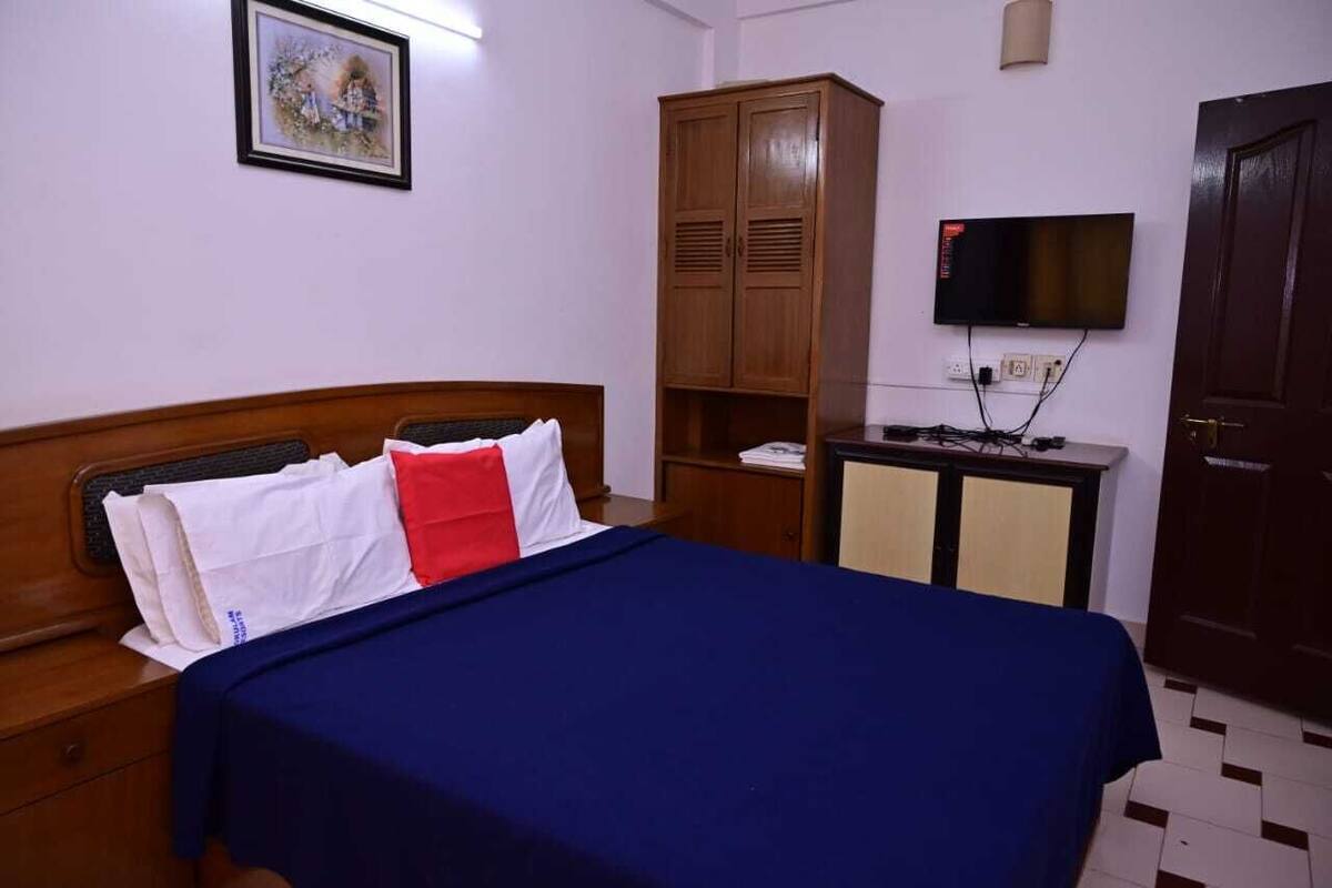 Un dormitorio con cama de madera, televisor, armario y escritorio con televisor de pantalla plana.