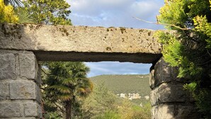 Une arche en pierre encadre une piscine, avec une statue en premier plan.
