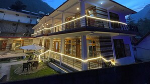 A two-story building with a balcony and outdoor seating area. - Woodward Magique kasol (Bhuntar)