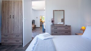 A bedroom with a bed, a wooden wardrobe, a dresser, and a mirror. - Villa Spirida at Drakopoulata (Kefalonia)
