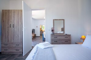 A bedroom with a bed, a wooden wardrobe, a dresser, and a mirror. - Villa Spirida at Drakopoulata (Kefalonia)