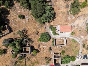 Vista aérea de un sitio histórico con ruinas, un edificio de techo rojo y vegetación circundante.