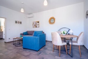 Una sala de estar moderna con un sofá azul, una mesita y un comedor con sillas.
