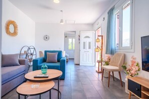 A modern living room with a blue sofa, a wooden coffee table, and a TV on the right. - Villa Spirida at Drakopoulata (Kefalonia)