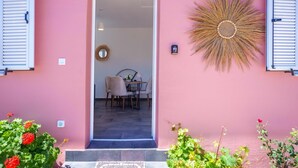 A pink exterior with a door leading to an interior dining area. - Villa Spirida at Drakopoulata (Kefalonia)
