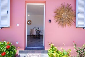 A pink exterior with a door leading to an interior dining area. - Villa Spirida at Drakopoulata (Kefalonia)