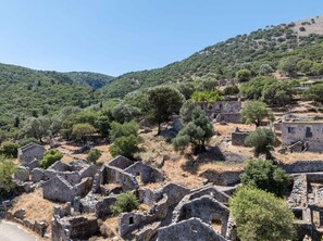 Ancient ruins with stone walls and scattered trees, set against a backdrop of hills and clear skies. - Villa Spirida at Drakopoulata (Kefalonia)