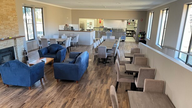 A spacious indoor area with a long dining table, several sofas, and a kitchen in the background. - san michele resort (Adaminaby)