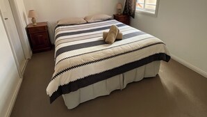 A bedroom with a bed, a nightstand, a lamp, a window with curtains, and a ceiling light. - san michele resort (Adaminaby)