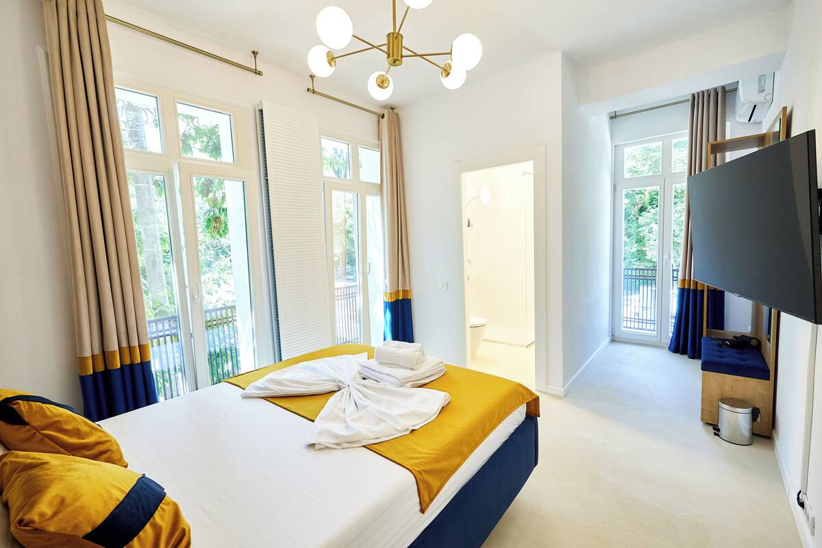 A hotel room with a bed, a television, and a window with curtains.