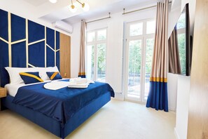 Et moderne hotelværelse med en stor seng, fjernsyn og en balkon med gardiner.