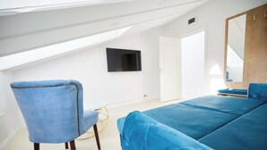 A room with a blue sofa, a blue armchair, a TV mounted on the wall, and a wooden door. - Carol Park View (Bucharest)