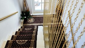 A staircase with patterned carpets and a view of a car outside. - Carol Park View (Bucharest)