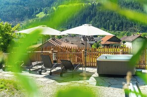 A patio area with outdoor furniture, a hot tub, and a wooden fence.