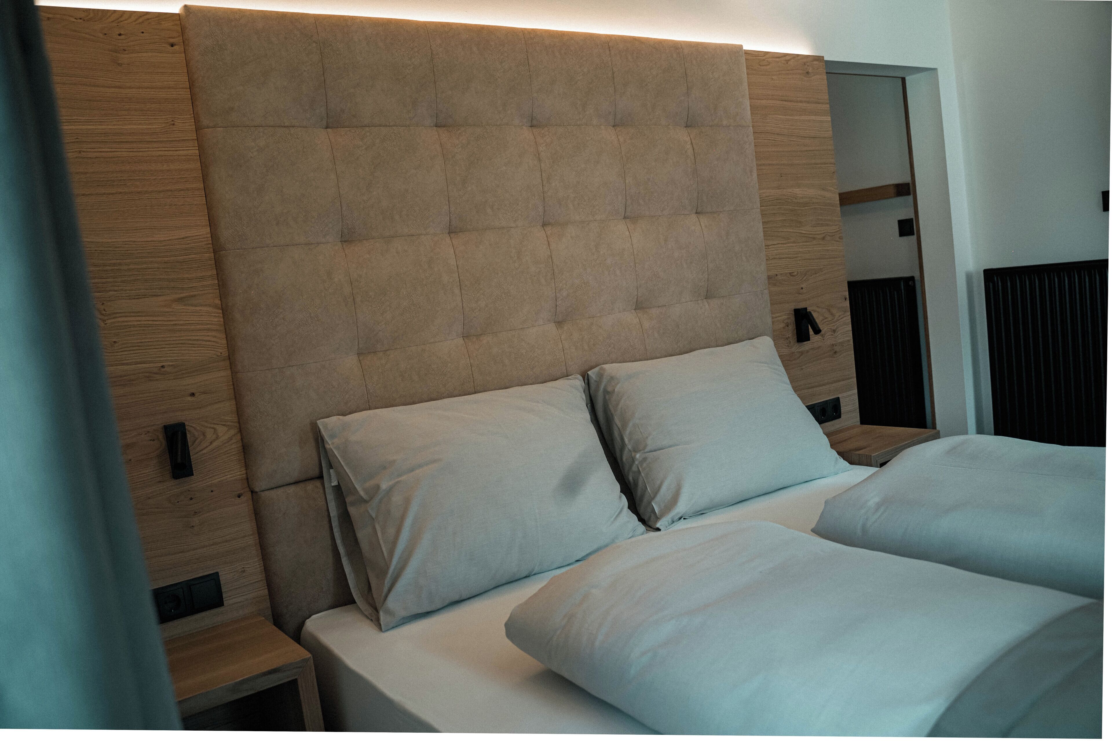 A modern bedroom with a tufted headboard, a wooden nightstand, and a bed with white linens.
