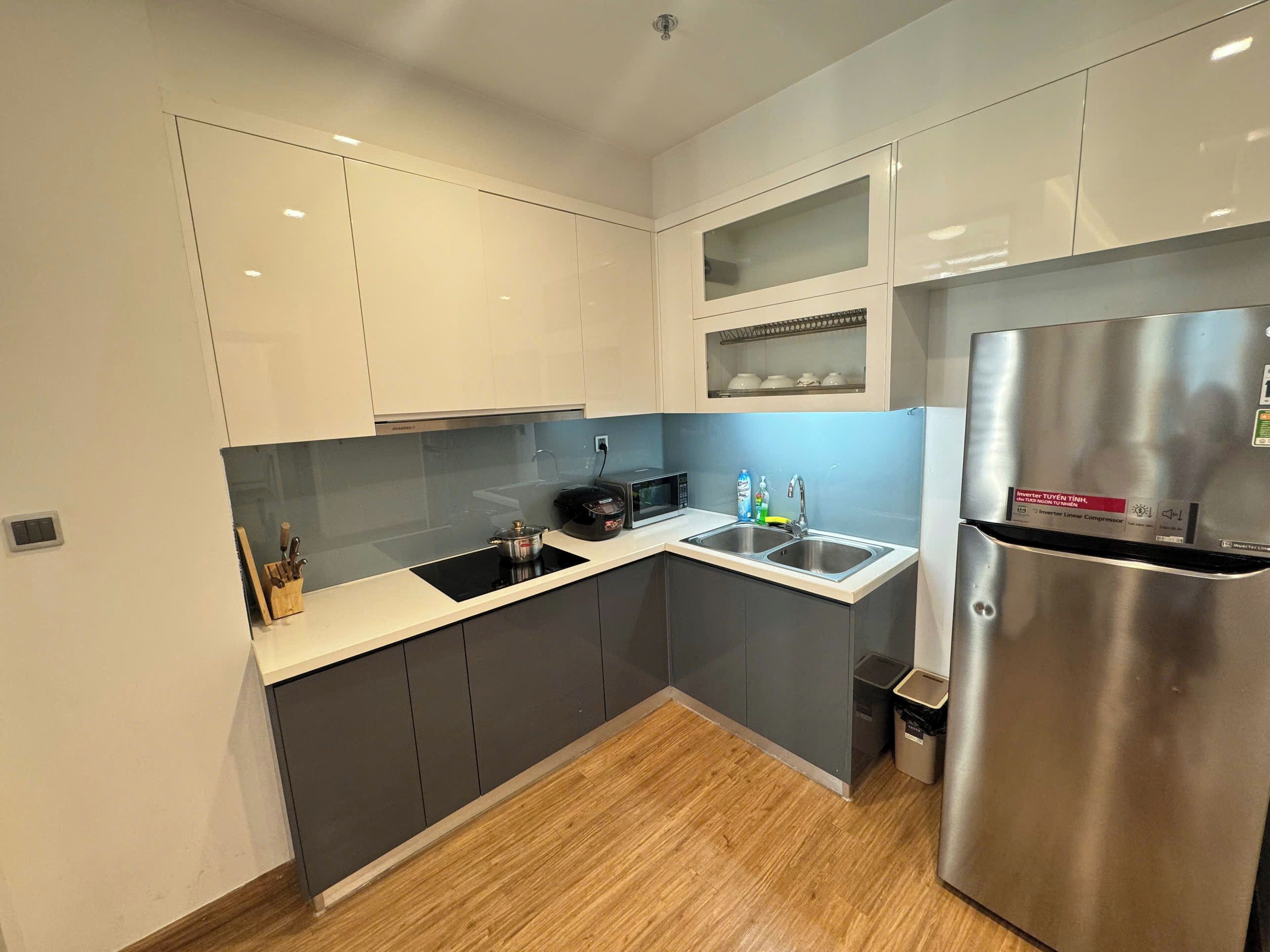 A modern kitchen with grey cabinets, a stainless steel refrigerator, and a microwave.