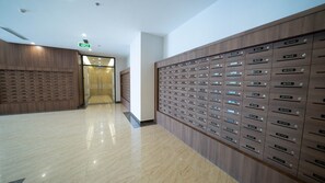 A modern hotel lobby with a long corridor, wooden lockers, and a glass elevator. - Luxury Apartment Metropolis NNP (Hanoi)