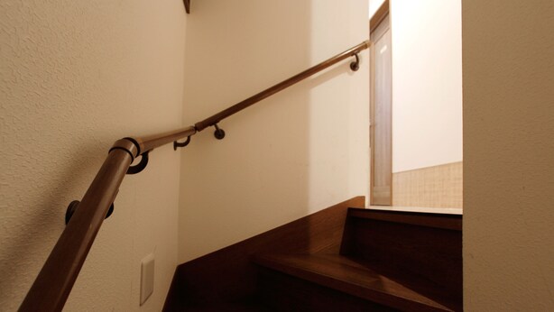 Una escalera de madera con barandilla y un interruptor de luz en la pared.