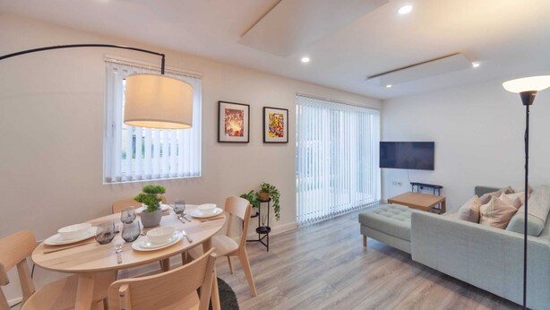 Una sala de estar moderna con comedor, que incluye un sofá, televisor y una mesa de comedor con platos y vasos.