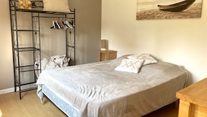 A bedroom with a bed, a wardrobe, a painting, and a small table.