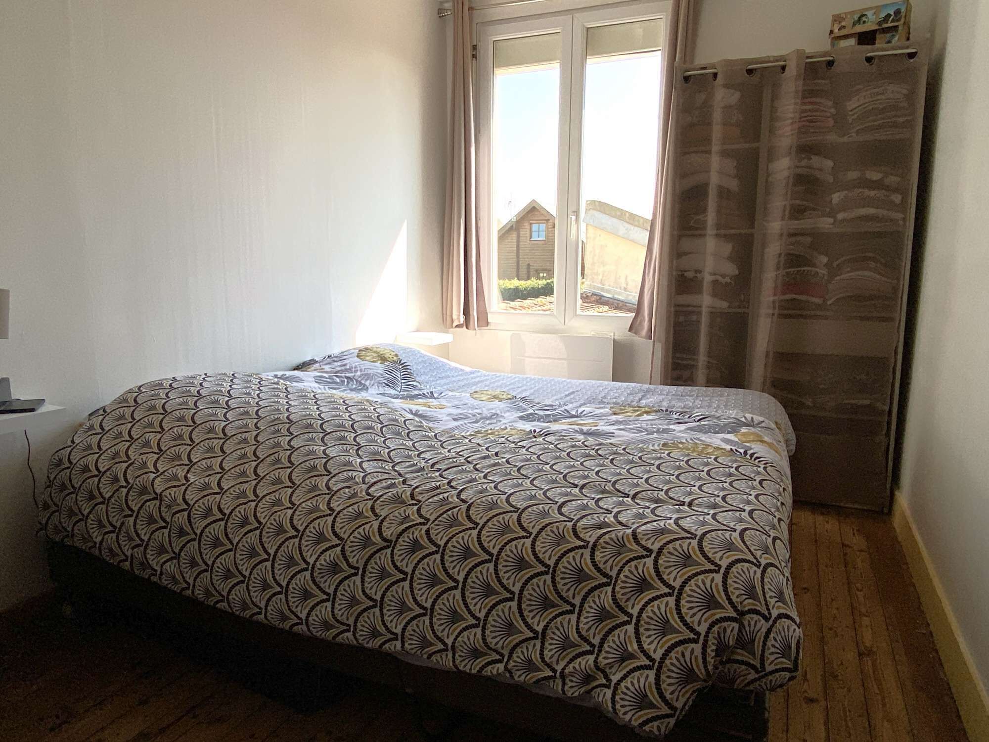 A bedroom with a bed, a window with curtains, and a view of the outside.