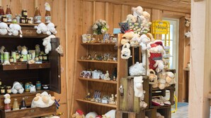 Un magasin avec des étagères en bois remplies de divers articles, notamment des bocaux, des tasses et des peluches.