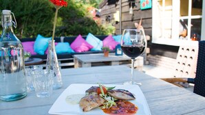 Une table à manger avec une assiette de nourriture, un verre à vin et des bouteilles.