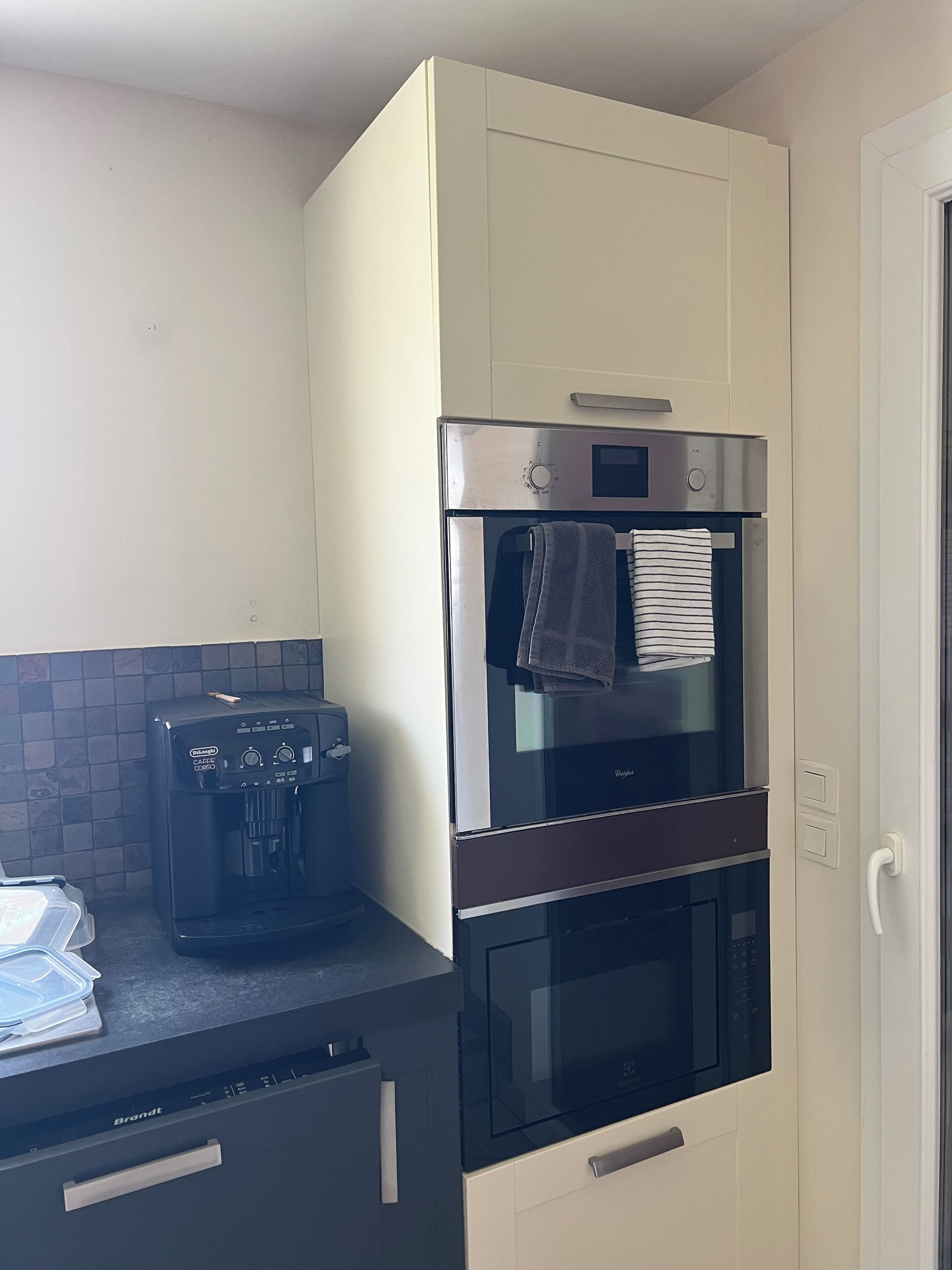 A compact kitchen with a coffee maker, a microwave, and a built-in oven.